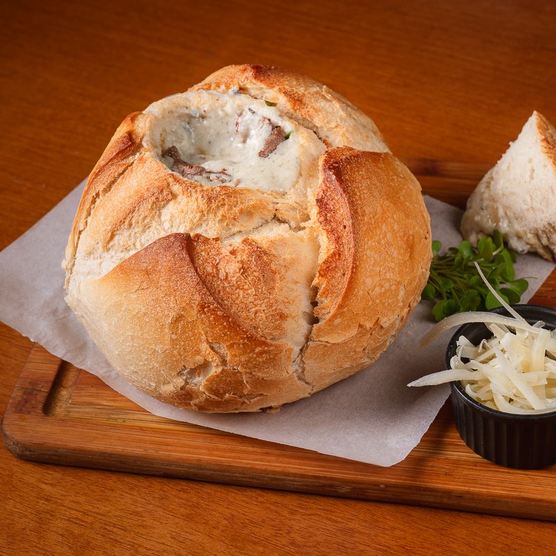 Creme servido dentro do pão italiano, com queijo ralado ao lado